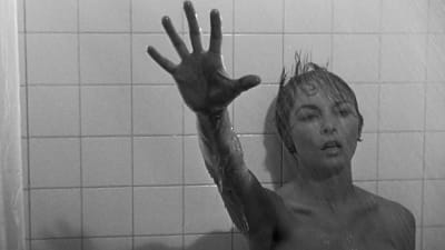 Nainen (Janet Leigh) nojaa suihkussa kaakeliseinään ja kurottaa kädellään kohti kameraa. Kuva elokuvasta Psyko.