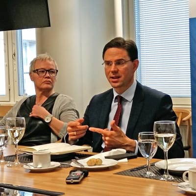 Jyrki Katainen sitter på en presskonferens och talar.