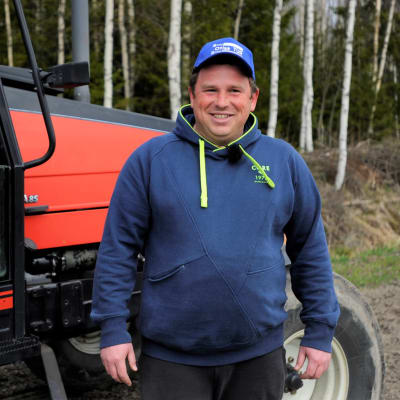 Vasyl Liutenko är säsongsarbetare från Ukraina. Står framför en traktor på en jordgubbsodling i Pörtom, Närpes, där han jobbar. 