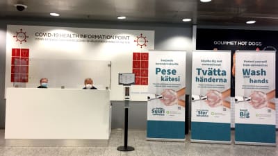 Två personer sitter bakom en disk vid Helsingfors-Vanda flygplats.