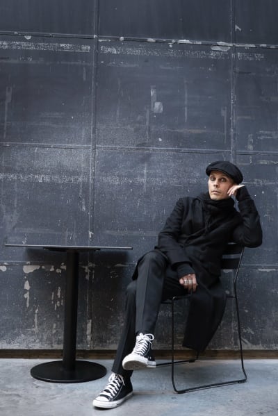 Ville Valo istuu rennosti tummanharmaan seinän edessä.