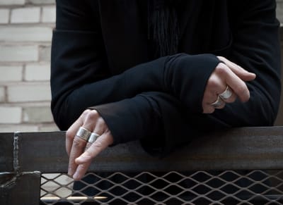 Ville Valon kädet, joissa paksuja hopeanvärisiä sormuksia lähikuvassa.