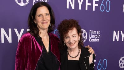 Närbild på Laura Poitras och Nan Goldin då de står på röda mattan och kramar om varandra och ler.