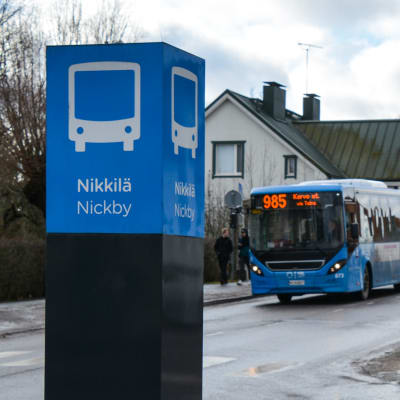 En blå stadsbuss kommer körande mot en busstation i Nickby centrum.