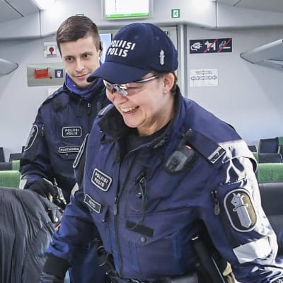 En polis kontrollerar en tågresenärs person- och reseuppgifter under coronavåren då Nyland var stängt.