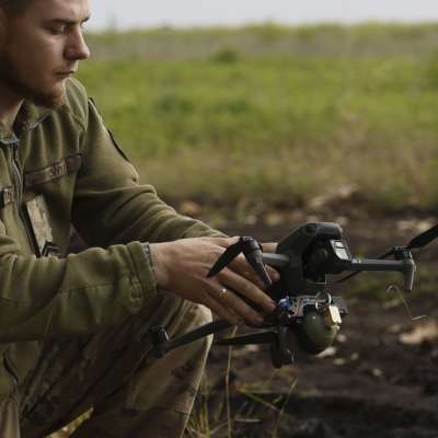 Ukrainsk soldat håller i en helikopterdrönare som bär på en handgranat.