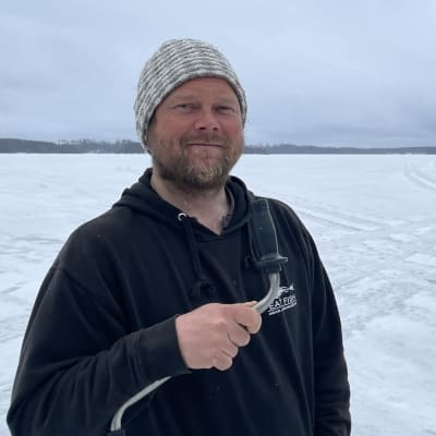 Kalastaja Pekka Rintamaa kaira kädessä jäällä.