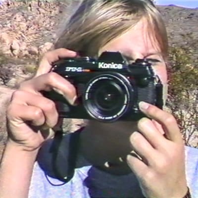 Eva Vitija fotograferad i unga år med en kamera framför ansiktet.
