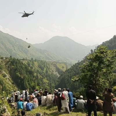Helikopter i färd med att rädda passagerar som fastnat i lift mellan två berg. 