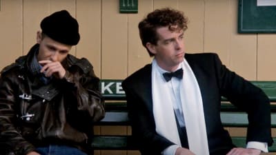 Pet Shop Boys -duo istuu ulkona. Kuva elokuvasta It Couldn't Happen Here.