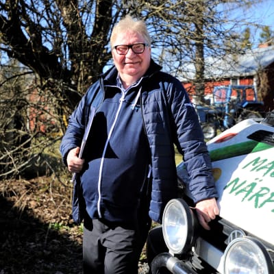 Raymond Wesander, med kalendern under armen, står lutad mot sin bil och njuter av majsolen