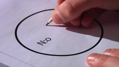 En hand som håller i en penna och är i beråd att fylla i en valsedel.