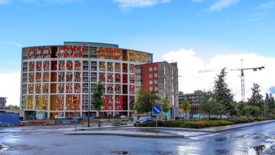Ett bumerangformat hus med färggranna fasadpaneler i rött, gult och orange. Byggnaden finns i Vanda i Kivistö.