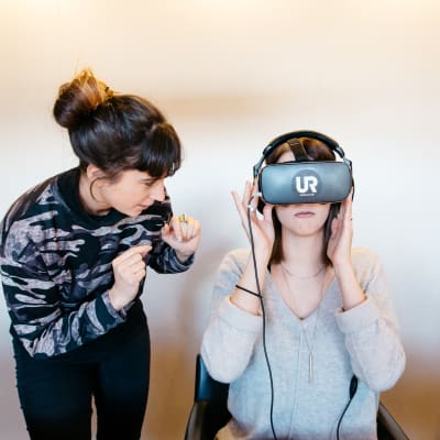 Saskia Oljelund näyttää UR:n tekemää koulukiusaamis-videoita, VR-silmikko päässä Jenna Karas