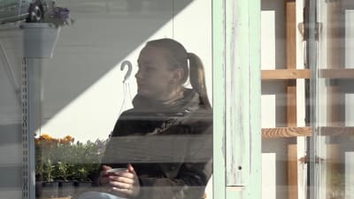 Blomförsäljerska i Iecava fotad genom fönstret.