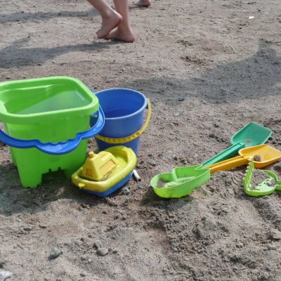 Flera plastleksaker i olika färger på en sandstrand