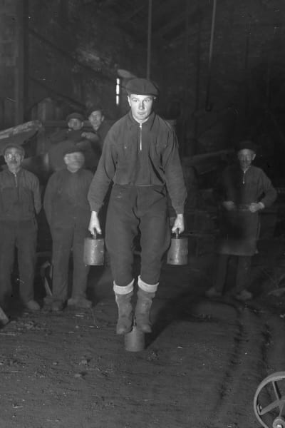 En man lyfter två tunga lod. Bilden är tagen 1936 i Strömfors bruk.