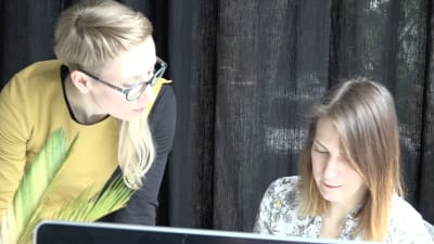 Anna Andersone tittar på hur en ung kvinna jobbar vid sin dator.