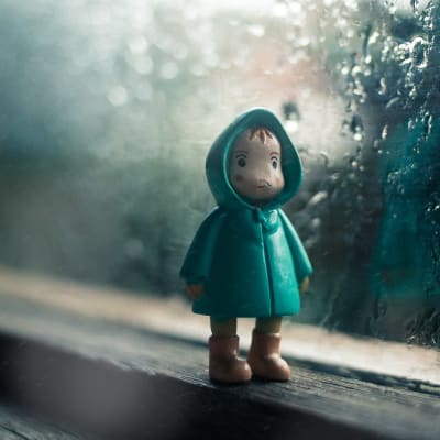 En modellfigur står på ett fönsterbräde med regn på fönstret i bakgrunden.