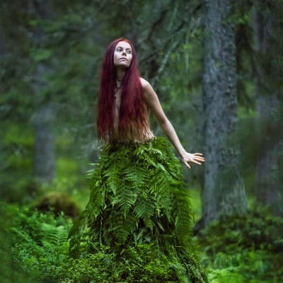 Musikern Venior i en skog iklädd en kjol av ormbunkar.