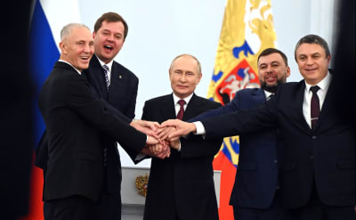 Rysslands president Vladmir Putin och fyra andra män håller varandra i händerna och firar att Ryssland annekterar delar av Ukraina.