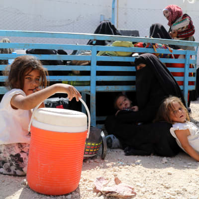 Syriska kvinnor och barn väntar på transport bort från det överfyllda lägret al-Hol i Syrien. Juni 2019.