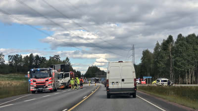 Räddningspersonal och räddningsfordon står vid en väg där det skett en olycka. Bilar väntar i kö.