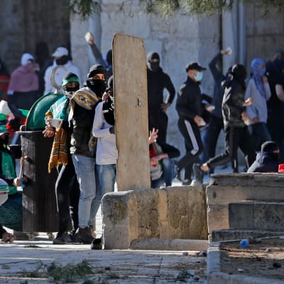 Unga palestinier kastade sten och försökte skydda sig mot polisernas gummikulor utanför Al-Aqsamoskén på fredag morgon. 