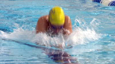 En simmare iförd gul simmössa och simglasögon.