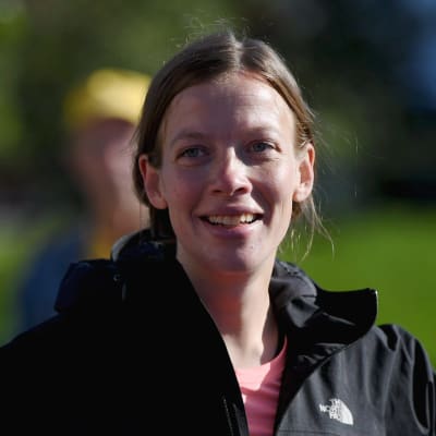 Li Andersson klädd i svart sportrock med händerna i sidorna och ett leende på läpparna.