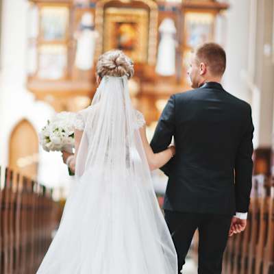 Brudpar går uppför altaret i en ståtlig kyrka.