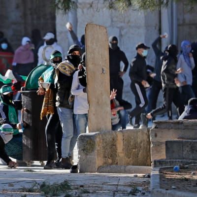 Unga palestinier kastade sten och försökte skydda sig mot polisernas gummikulor utanför Al-Aqsamoskén på fredag morgon. 