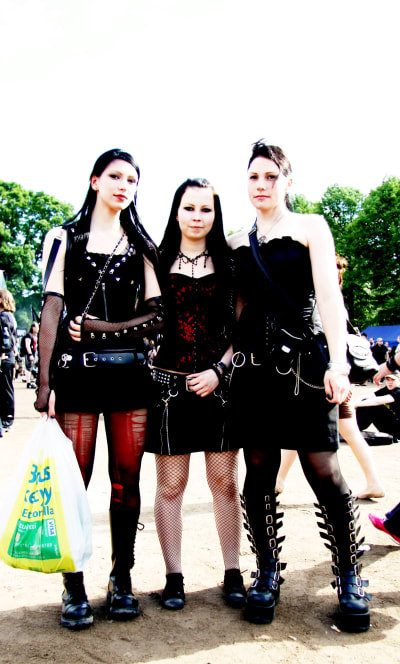 Tre unga kvinnor i läderkorsetter på hårdrocksfestival.