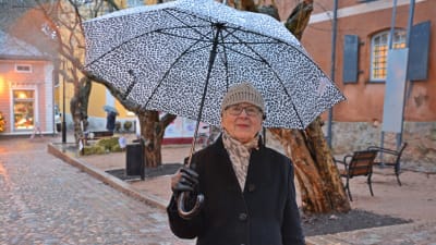 En dam med leopard-mönstrat paraply står i Gamla stan i Borgå.