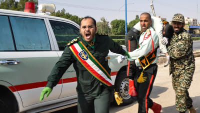 Iranska soldater bär bort en sårad kamrat efter attacken mot en militärparad i Ahvaz, lördagen 22.9.