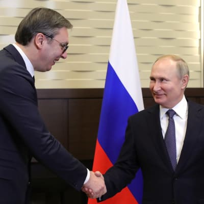 Aleksandar Vucic ja Vladimir Putin kättelevät maidensa lippujen edessä