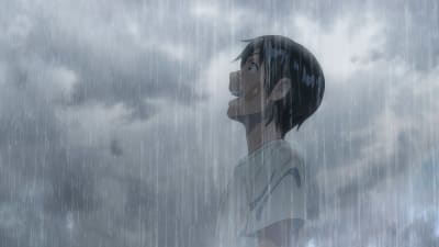Pojken Hodaka står i ett grått regn och ser skrattande upp mot himlen.