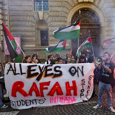 Demonstranter som håller palestinska flaggor och en banderoll med texten "All eyes on Rafah".