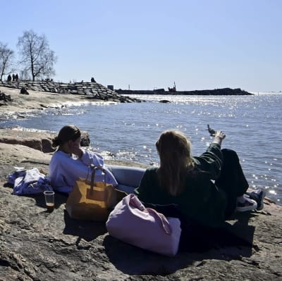 Människor njuter av det soliga vårvädret vid Eira strand i Helsingfors den 18 april 2021.