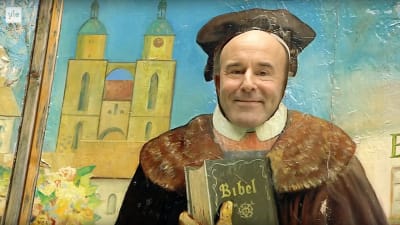 Mark Levengoods ansikte bakom en pappfigur av Marthin Luther.