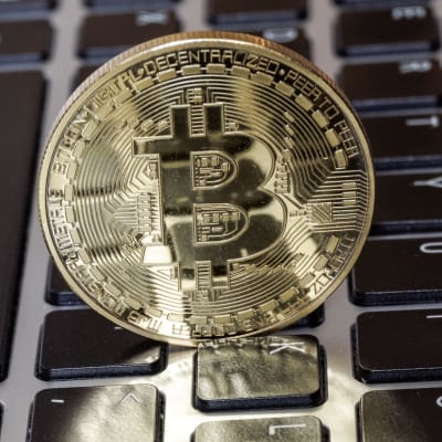 Ett mynt med symbolen för kryptovalutan Bitcoin ovanpå en laptops tangenter.