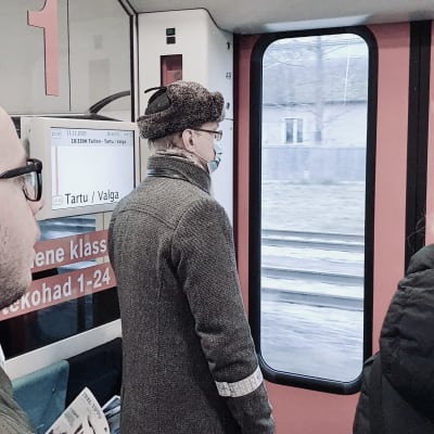 Passagerare på tåget mellan Tartu och Tallinn har ställt sig vid tågets dörr för att köa för avstigning.