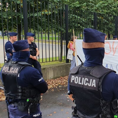 Delvis maskerade polska polismän övervakar en fredlig flyktingvänlig demonstration utanför Polens inrikesministerium.
