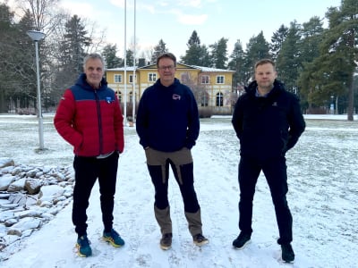 Tre män står på en vintrig innergård.