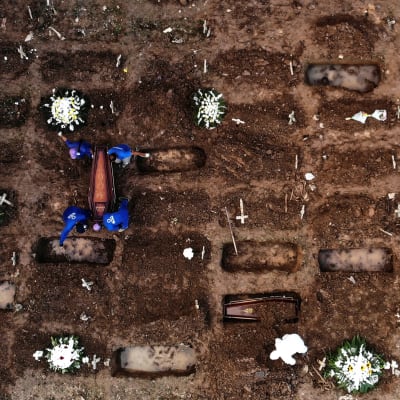 Bild tagen med drönare på en gravgård där coronadödsoffer begravs av personer i skyddsutrustning.