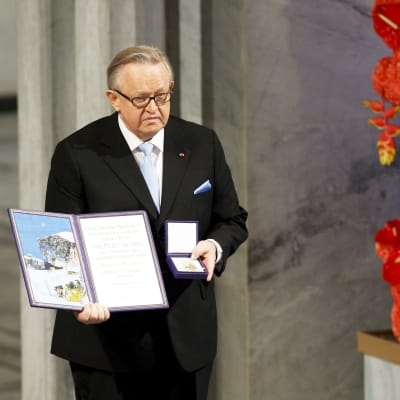 Martti Ahtisaari seisoo lavalla Nobel-palkinto kädessään.