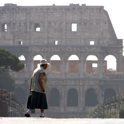 En kvinna korsar gatan intill Colosseum i Rom-