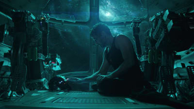 Iron Man sitter på golvet i en rymdfakost och tittar på sin hjälm.