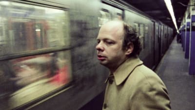 Wallace Shawn seisoo maanalaisen asemalla, juna ohittaa hänet. Kuva elokuvasta Ilta Andrén kanssa.