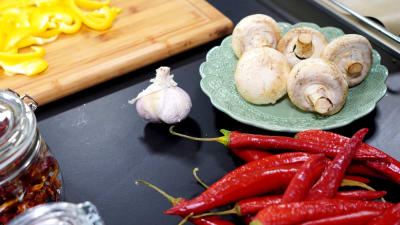 Vitlök, svamp och chili på ett bord.